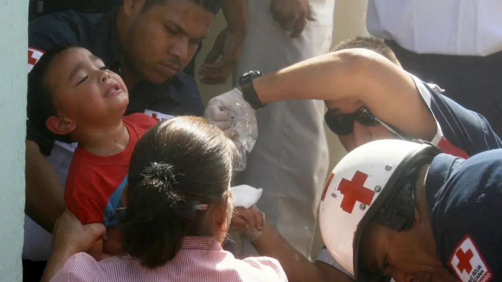 Socorristas de Cruz Roja de México evacúan a un niño de la guardería