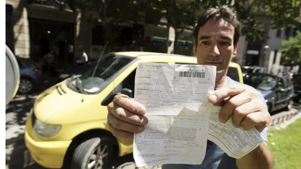 Andrés Espiño, junto a otro vehículo de su empresa, muestra la multa que le pusieron el viernes.
