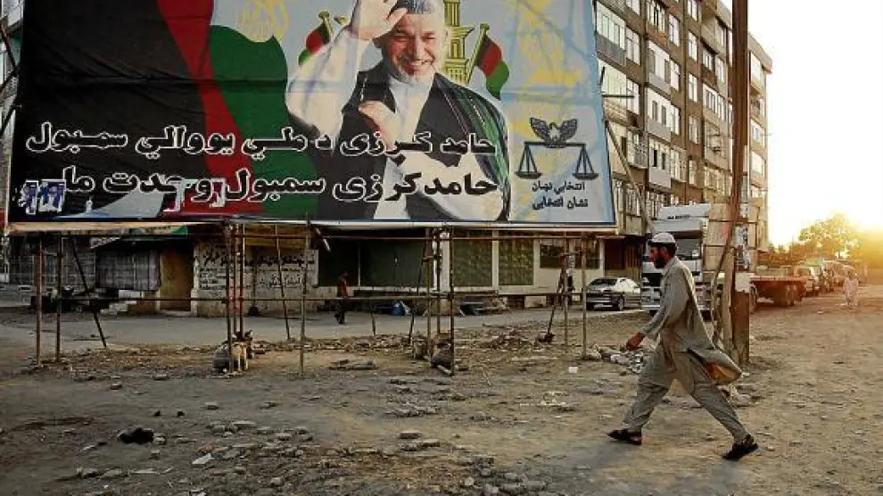 Un hombre pasa frente a un cartel electoral del presidente afgano Karzai, en Kabul.