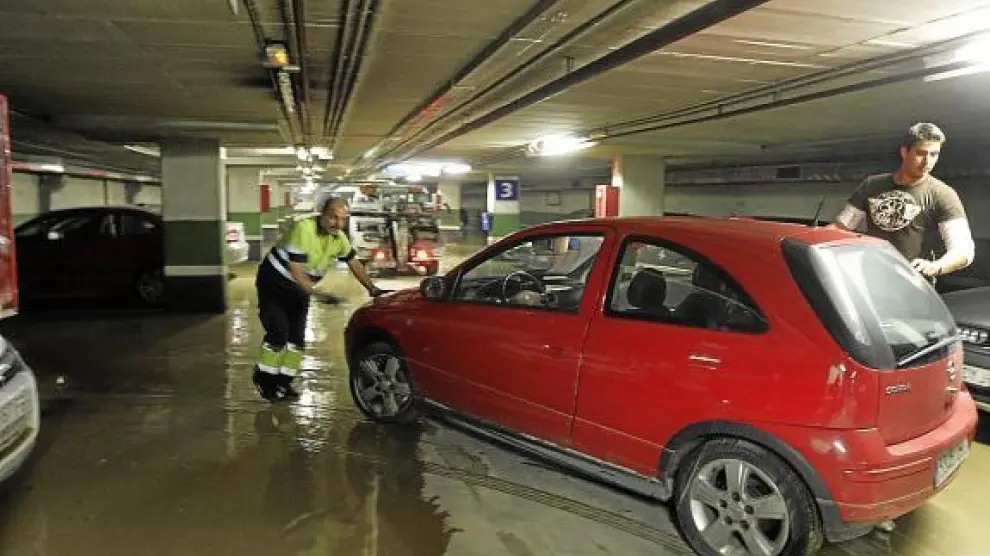 Una grúa retira del aparcamiento uno de los vehículos afectados por la inundación.