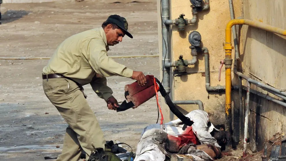 Un agente pakistaní retira el chaleco de uno de los terroristas suicidas