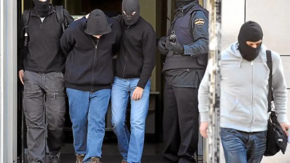 Dos agentes trasladan a uno de los detenidos a un coche policial en San Sebastián.