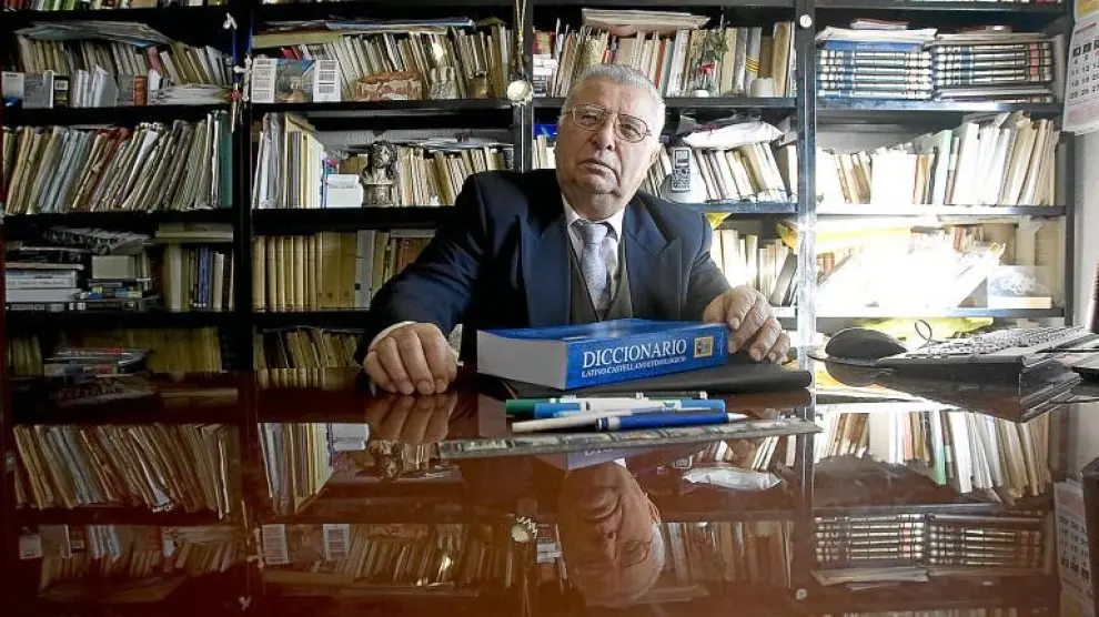 Pascual Martínez, en su mesa de trabajo. Su último libro en la mesa y, en las estanterías, muchísimos más.