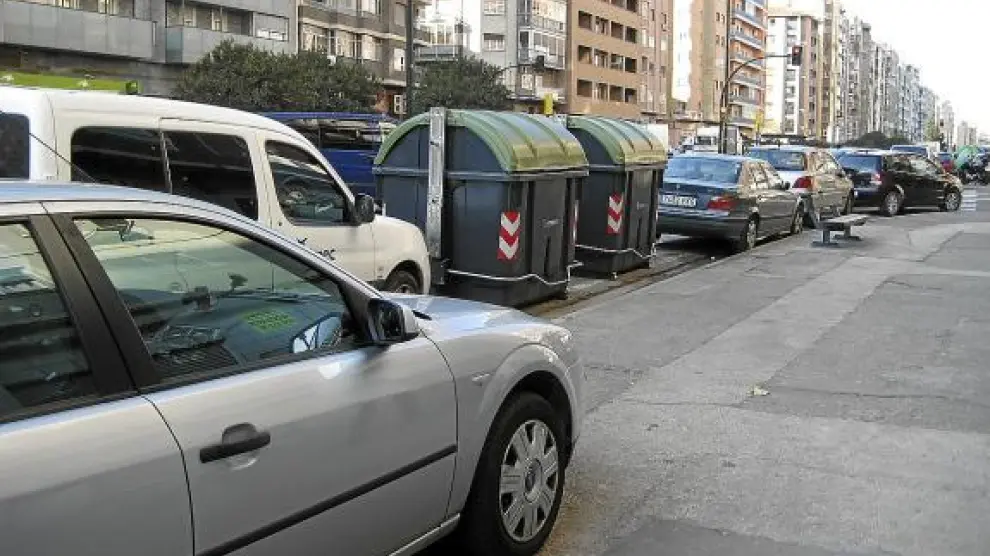 Contenedores y coches aparcados en el carril derecho e, incluso, sobre la acera, en la avenida de Navarra.