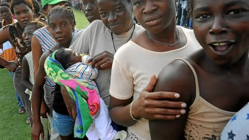 Mujeres y niños hacen cola en un punto de distribución de comida, ayer en Puerto Príncipe.