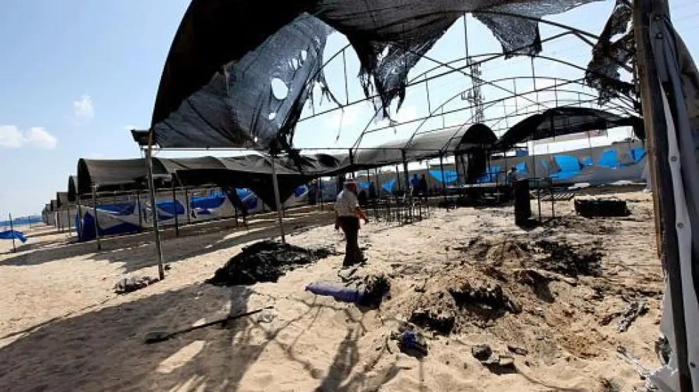 Un trabajador de la ONU inspecciona los restos del campamento quemado.