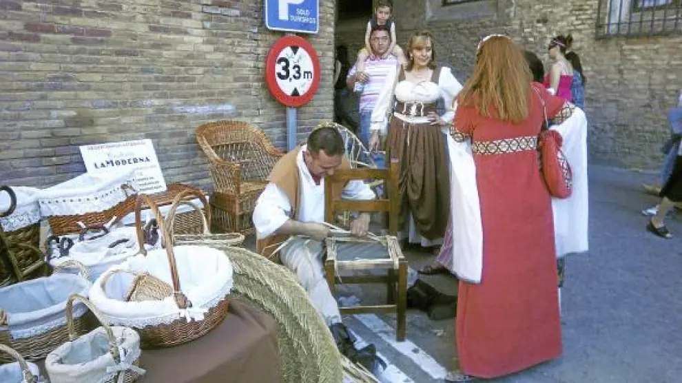 Un artesano elabora una cesta en uno de los puestos del mercado medieval.