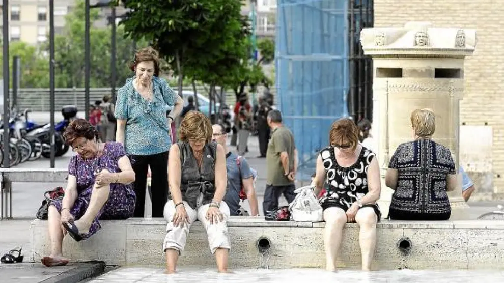 Unas mujeres se refrescaban ayer los pies en la plaza del Pilar de Zaragoza.