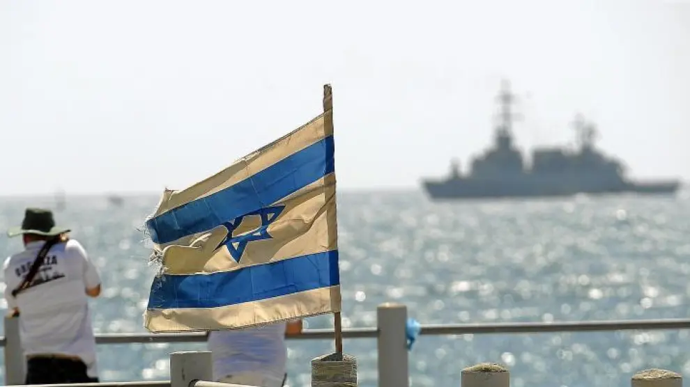 Unos israelíes observan, junto a la bandera de su país, el buque 'Rachel Corrie', que ayer fue abordado por el Ejército.