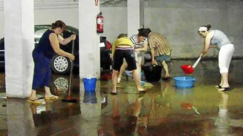 Los vecinos achican agua en el garaje de un edificio de Grañén.