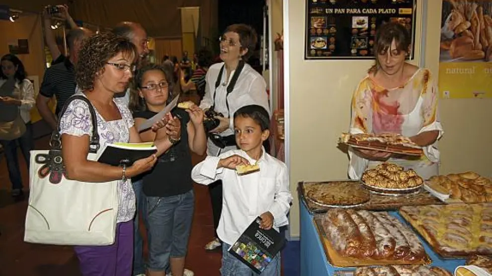 Varios visitantes degustan dulces de Velilla de Cinca en uno de los puestos de la feria.