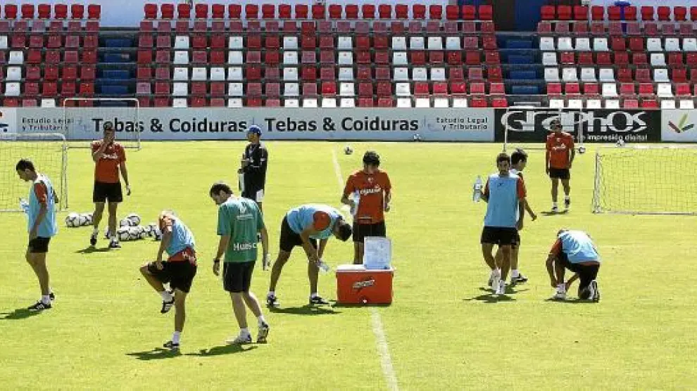 Los jugadores del Huesca, durante un interludio del entrenamiento de ayer durante el que se hidratan con agua.