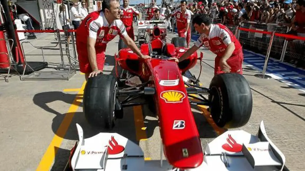 Los mecánicos de Ferrari empujan el monoplaza de Fernando Alonso a boxes del circuito de Valencia.