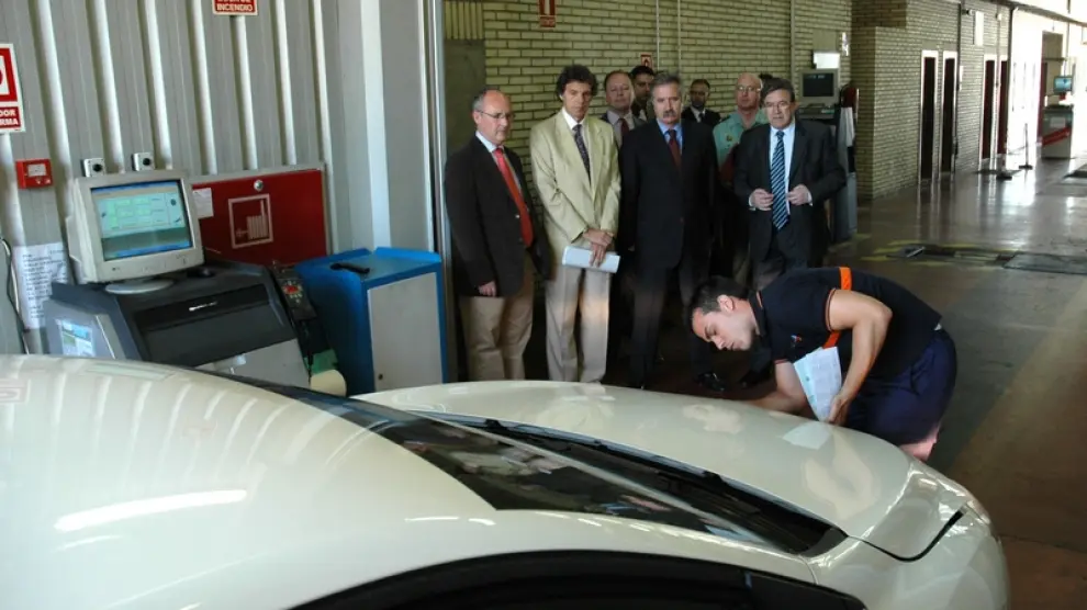 Un trabajador de la estación de Malpica revisa un vehículo bajo la atenta mirada de los miembros del Gobierno de Aragón durante su visita