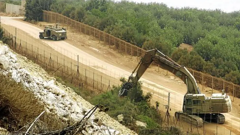 Una grúa del Ejército israelí tala árboles, ayer en la frontera próxima al poblado libanés de Adeise.