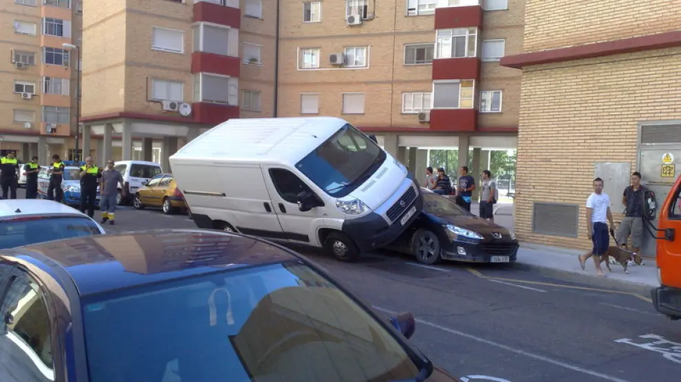 Una furgoneta se ha subido encima de un coche aparcado
