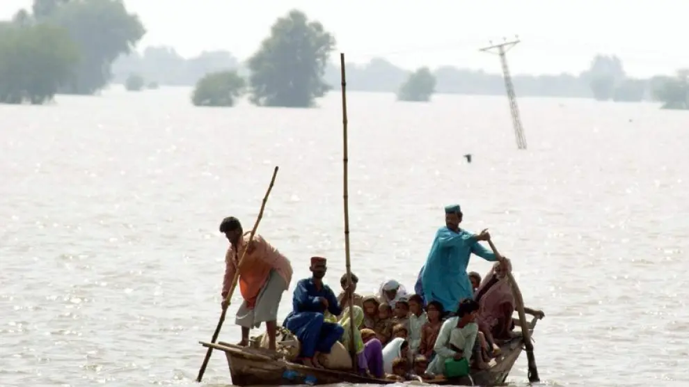 Varias personas se trasladan en una barca por una zona inundada