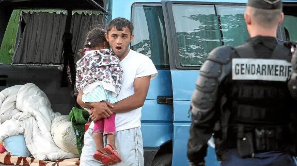 Un policía observa a un gitano rumano con una niña, el 19 de agosto en Saint Martin d'Heres.