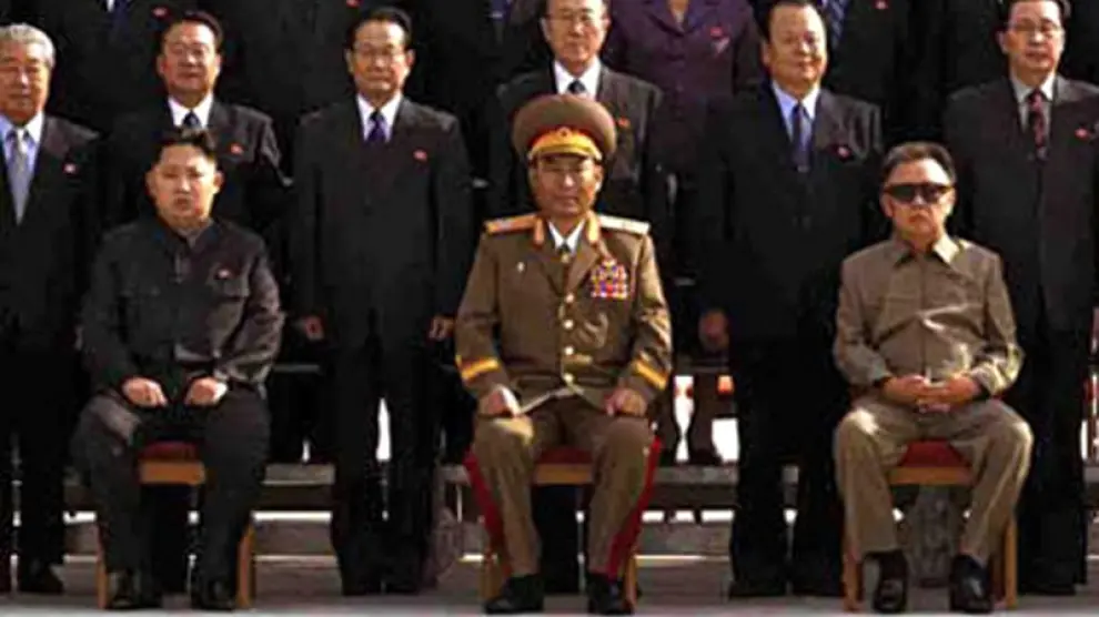 Kim Jong-Un, sentado a la izquierda, con gesto serio y rígido
