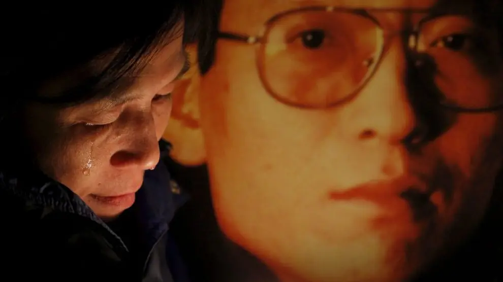 Una activista llorando junto a una foto del disidente chino Liu Xiaobo.