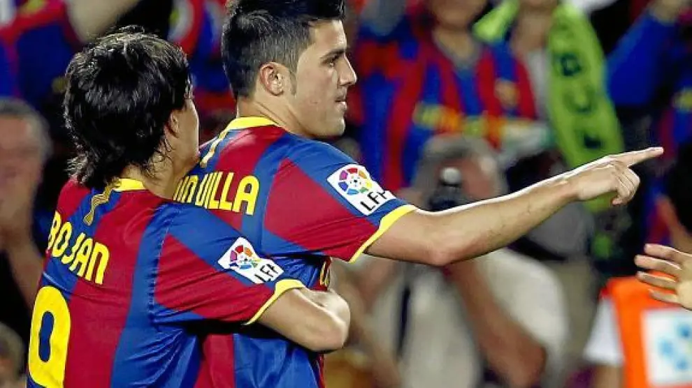 Bojan abraza a David Villa tras marcar un gol al Sporting.