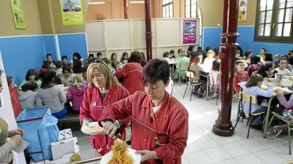 Una monitora sirve un plato de pasta en el comedor del colegio Gascón y Marín de Zaragoza.