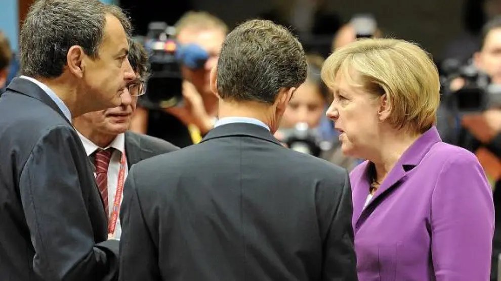 Zapatero conversa con Merkel y Sarkozy (de espaldas), ayer, en la cumbre de Bruselas.