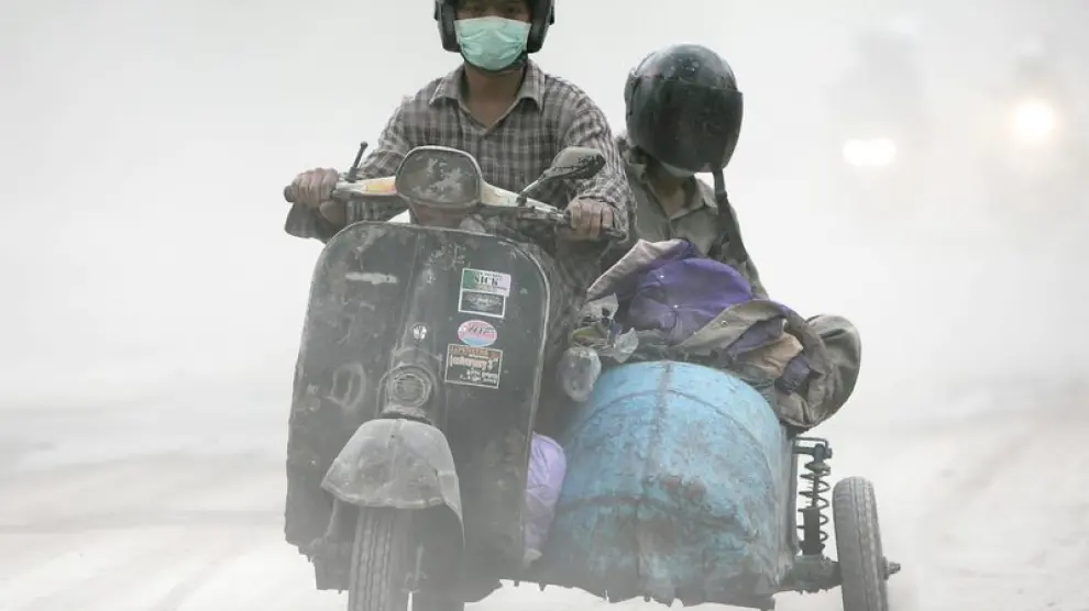 Dos hombres transitan en moto por una calle llena de ceniza en Yogyakarta