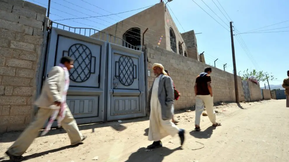 Transeúntes pasan junto a la casa donde vivía la estudiante detenida en Yemen por su relación con los explosivos