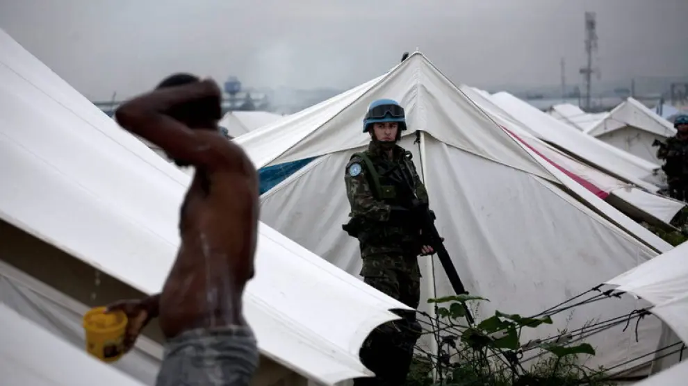 Un hombre se lava ante la atenta mirada de un soldado, ayer, en el campamento de Cite Soleil, Puerto Príncipe