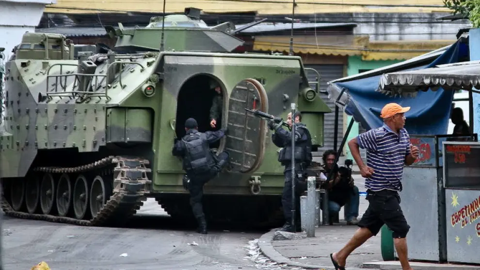 Varios policías prestan guardia junto a un vehículo de las Fuerzas Armadas en una de las zonas conflictivas de Río de Janeiro