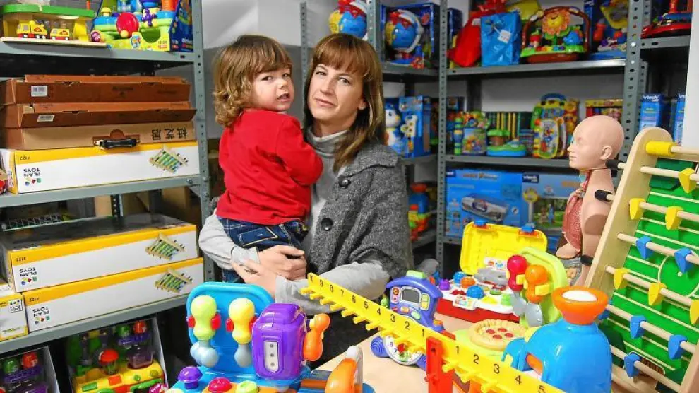 Magda, con su hijo pequeño en brazos, y rodeada de los cientos de juguetes que ofrece a través de su empresa de alquiler.