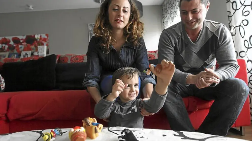 Javier coge un muñeco con su nueva mano bajo la atenta mirada de sus padres, Alicia Orce y Rubén Gimeno.