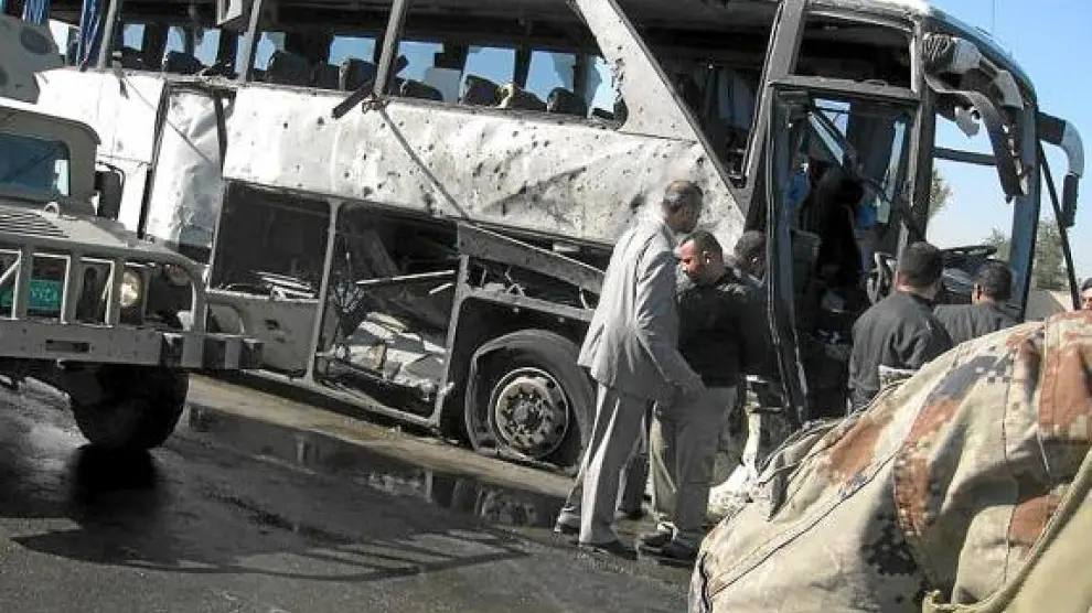Iraquíes inspeccionan los restos de un autobús objetivo de un atentado en Bagdad, el sábado.
