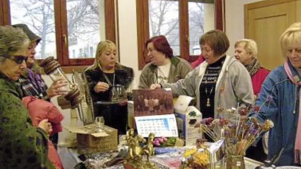 Varias mujeres ojean los objetos a la venta en el rastrillo.