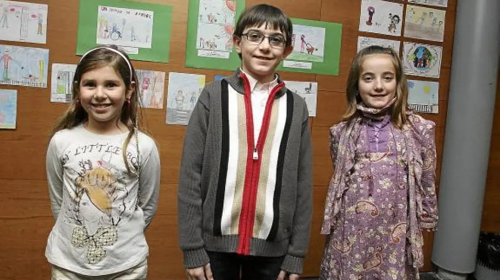 Los tres niños premiados posan delante de sus dibujos, con los que ilustran la igualdad.