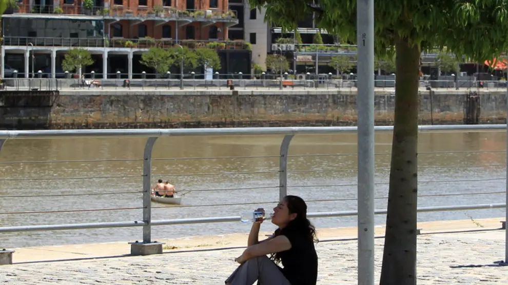 Una mujer se refresca a la sombra de un árbol, hoy en Buenos Aires