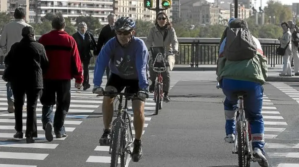 Tres ciclistas en un paso regulado por semáforos junto al puente de Santiago.