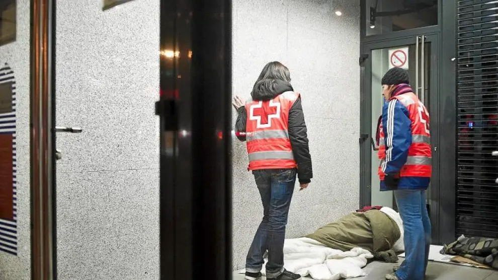 Dos voluntarios de Cruz Roja atienden a una persona sin hogar en Zaragoza.