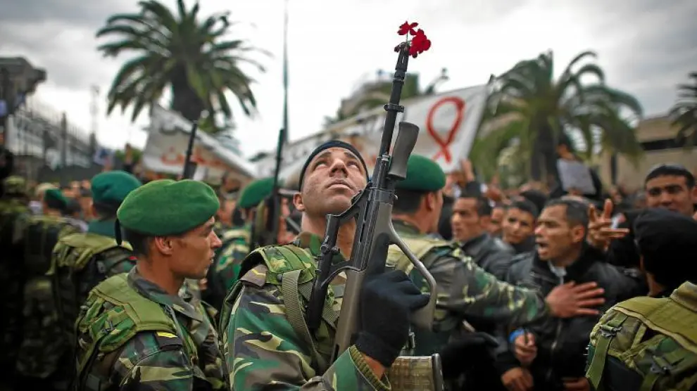 Un militar tunecino, con una flor en su arma, mira hacia el cielo durante la concentración ante la sede del partido RCD.