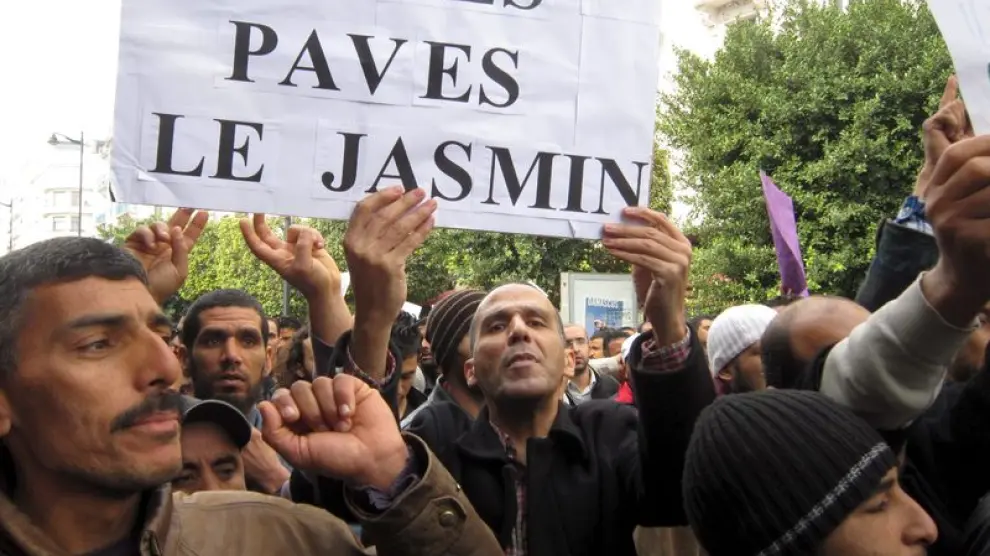 Tunecinos se manifiestan con una pancarta que dice en francés "Encima de las piedras, hay un jazmín"
