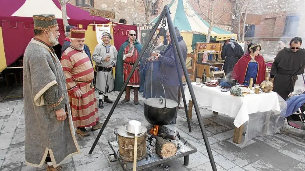 Miembros de uno de los grupos cocinando en la calle, con las jaimas al fondo, en la pasada edición de las Bodas de Isabel.