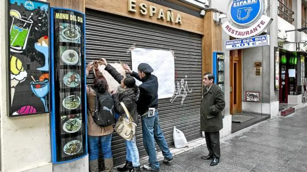 Algunos empleados colocaban ayer carteles reivindicativos en la puerta del bar España.