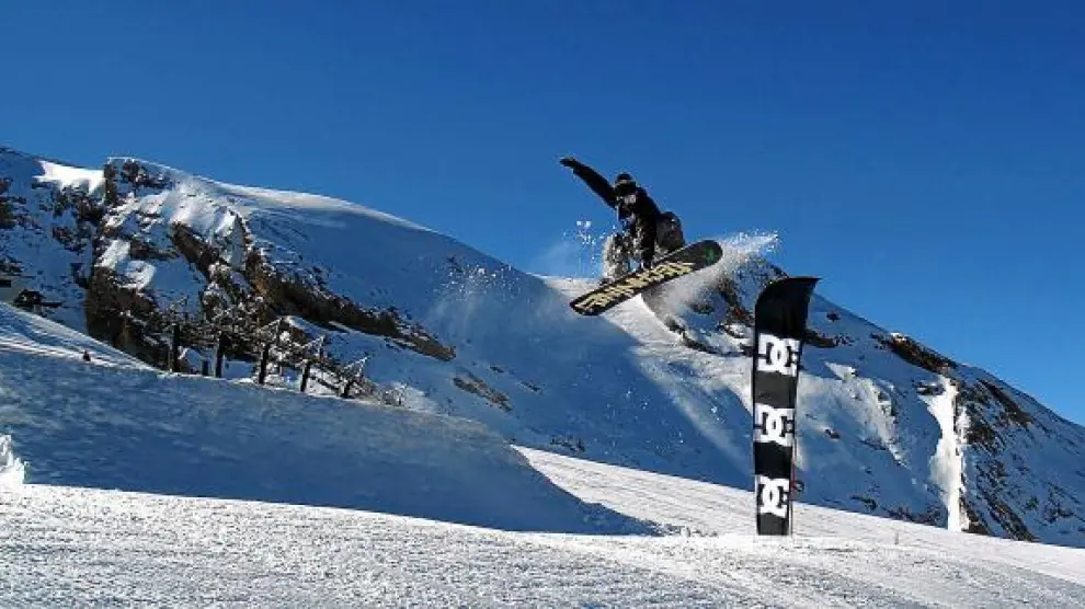 Un snowboard 'vuela', tras saltar uno de los módulos diseñados en el snowpark, en la pista de Basibé de la estación de esquí de Cerler.