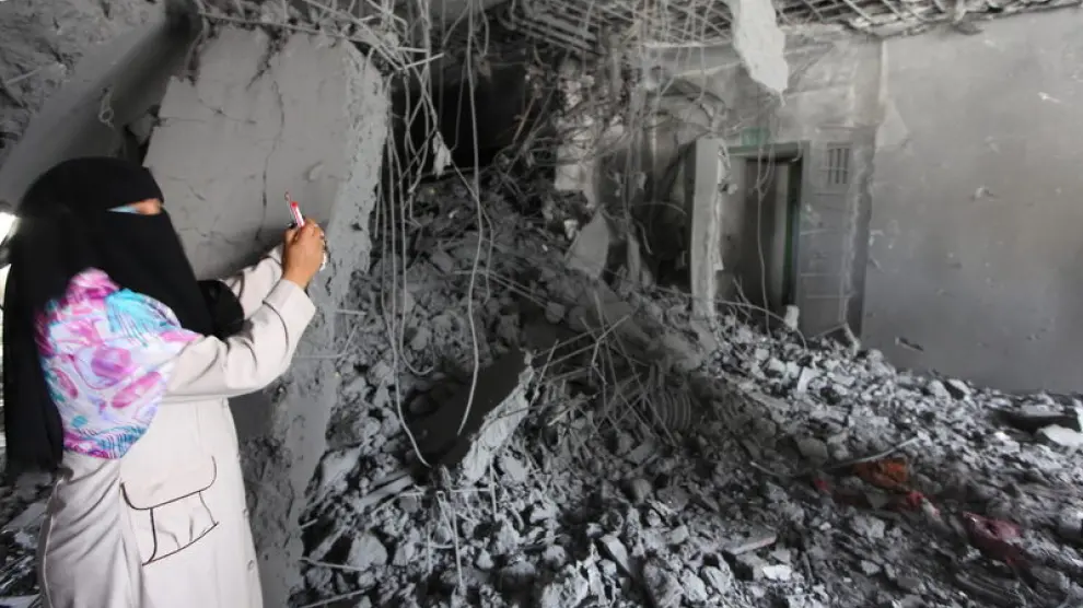 Una mujer fotografía su casa en Tripoli tras los bombardeos