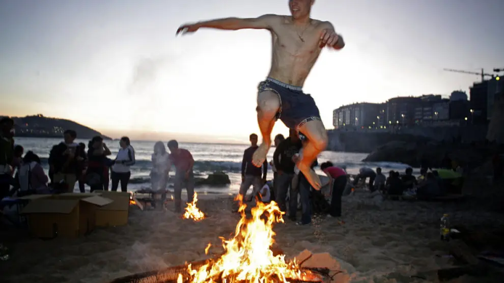 Un joven salta una hoguera en una playa de La Coruña.