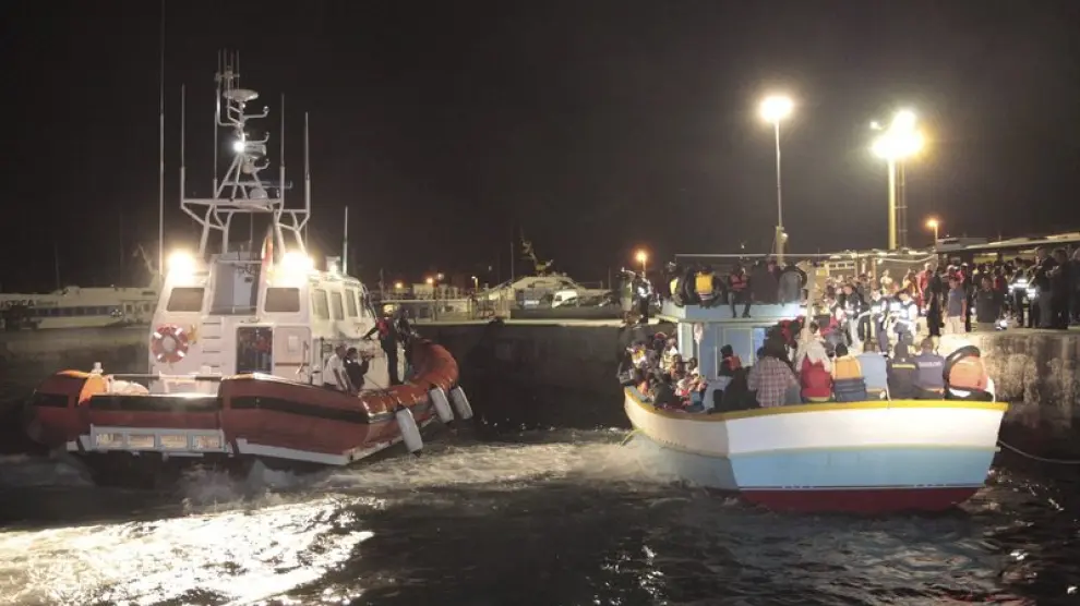Un barco de la guardia costera italiana (i) escolta a una de las cuatro embarcaciones que trasladan a emigrantes del norte de África a su llegada a la isla de Lampedusa