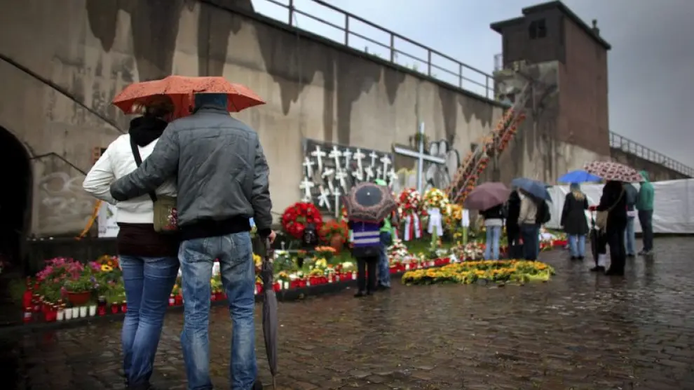Varias personas muestran sus respetos por las víctimas de la tragedia de la 'Loveparade' en su primer aniversario.