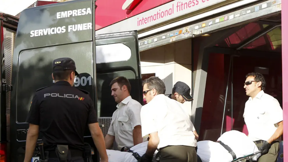 Tres empleados de los servicios funerarios trasladan el cadáver del fallecido.