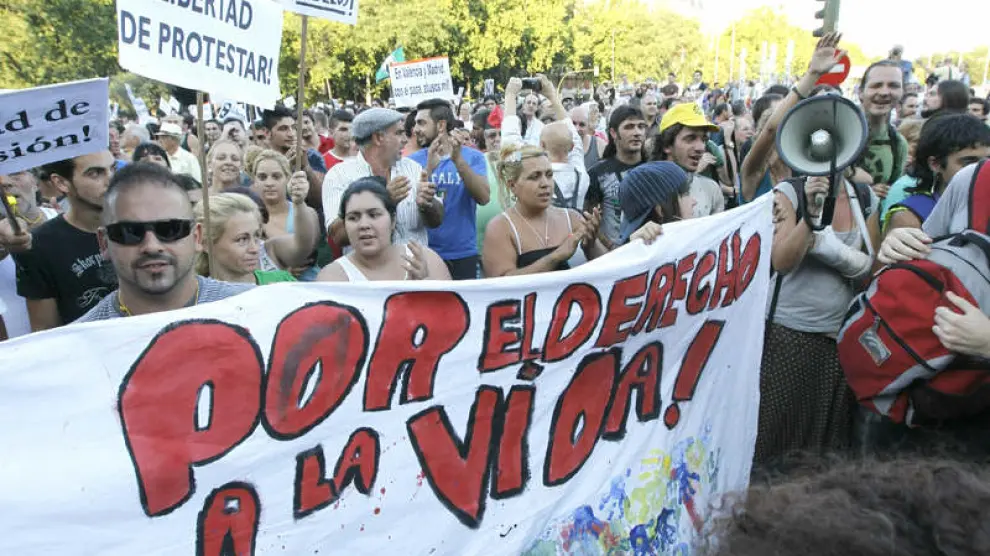 Varios indignados muestran su pancarta durante la concentración en la Plaza de Atocha